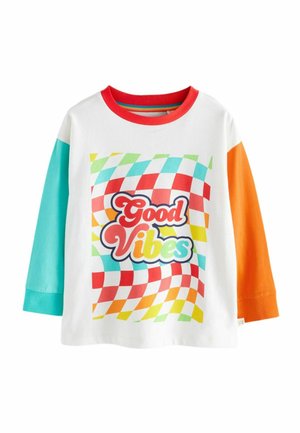 Maglietta bianca a maniche lunghe con maniche rosse, turchesi e arancioni. Presenta un vivace motivo a scacchi e il testo "Good Vibes" in grassetto.
