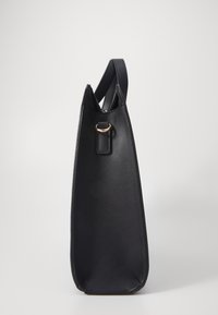 Sac à main en cuir noir avec une forme géométrique structurée. Doté d'un fond plat et d'un haut étroit, avec un accent en métal doré.