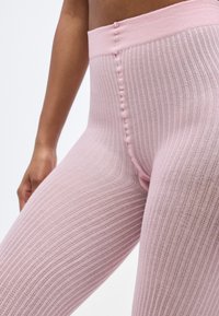 Ροζ ριμπ κολάν με ψηλή μέση, διαθέτει υφασμάτινη επιφάνεια και λεπτομέρειες με κουμπιά στο πλάι για επιπλέον ενδιαφέρον.