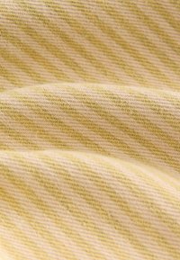 Tissu jaune clair avec des rayures diagonales dans une teinte plus douce, présentant un tissage texturé et une surface lisse.