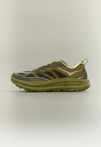 Αθλητικό παπούτσι ελιάς με άνω μέρος από δίχτυ, υφασμένο πέλμα, κορδόνια, αντανακλαστικές λεπτομέρειες και λογότυπο Vibram στη φτέρνα.