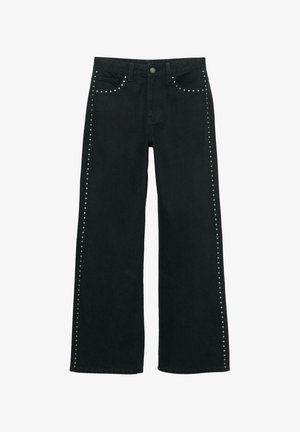 Crne traperice širokih nogavica s metalnim zakovicama duž bočnih šavova. Izrađene od trapera s klasičnim dizajnom s pet džepova.