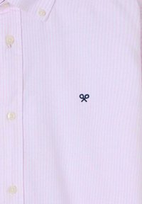 Camisa de botones a rayas de color rosa claro con cuello. Presenta un pequeño detalle bordado de un lazo en azul marino en el lado izquierdo y botones beige.