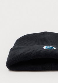 Czarna dziana czapka z prążkowanym wykończeniem i zaokrąglonym kształtem. Posiada mały haftowany wzór w niebieskim i białym kolorze z przodu.