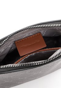 Portafoglio grigio con zip, con un esterno texture, etichetta in pelle all'interno e una fodera a fantasia che mostra molteplici scomparti.