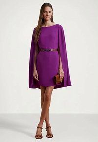 Vestido roxo com capa, design ajustado e cinto. Textura suave, comprimento curto, combinado com uma bolsa castanha e sandálias de salto bege.