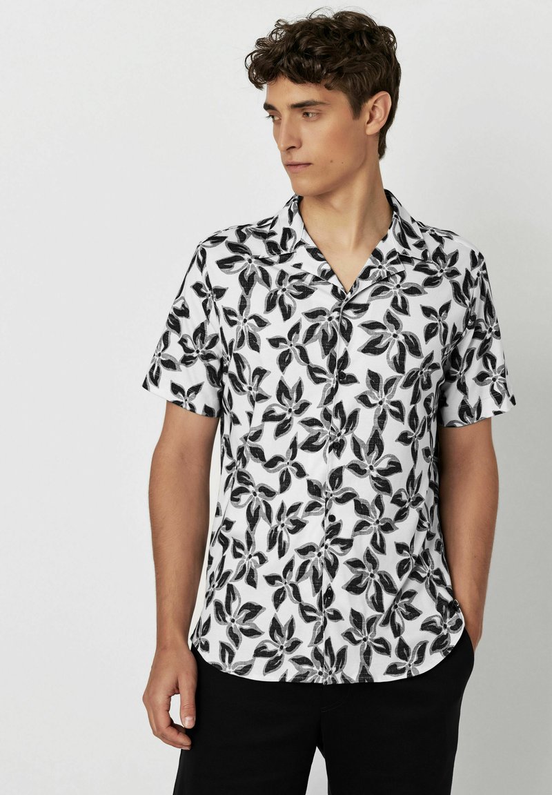 Kurzärmliges Hemd mit Knopfleiste aus weißem Stoff mit schwarzen Blattmustern, mit angedeutetem Kragen, lockerer Passform und standardmäßiger Säume.