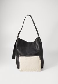 Bolsa de ombro em couro preto com uma textura suave, apresentando uma bolsa bege com fecho anexada na frente. Design simples e forma arredondada.