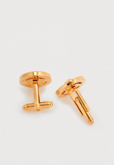 Μανικετόκουμπα σε χρυσό τόνο με κυκλικό σχέδιο, διαθέτουν λεία επιφάνεια και περιστρεφόμενο μανταλάκι για το κλείσιμο. Η λαμπερή μεταλλική επιφάνεια ενισχύει την εμφάνιση.