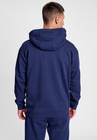 Marinblå hoodie i bomullsblandning, med en rymlig huva, ribbade ärmslut och nederkant, samt en enfärgad textur utan synliga mönster.