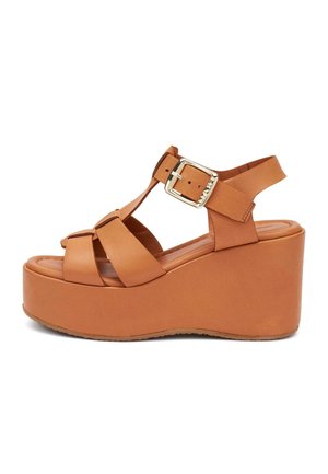 Sandalia de plataforma de cuero marrón con tiras gruesas, hebilla en el tobillo y tacón cerrado tipo cuña.