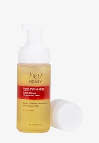 Reinigingsschuim in een transparante gele fles met een witte pomp. Heeft een rode label met de productnaam en details over het huidtype. 150 ml.