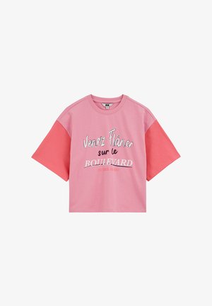 Rózsaszín, rövid fazonú póló sötétebb rózsaszín rövid ujjakkal, elöl fehér és fekete színnel nyomtatott francia szöveg: "Venez Flâner sur le Boulevard".