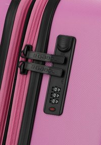 Rozekleurige koffer met een textuur oppervlak, zwarte ritsen en een combinatie-slot. Heeft verhoogde letters op de rits-trekker en een ingebouwd slotdisplay.