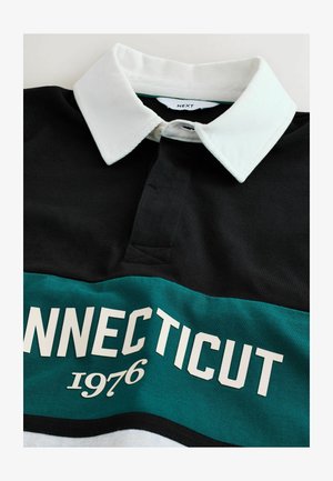 Svart polo skjorta med en vit ribbad krage, som har en teal horisontell rand med texten "CONNECTICUT 1976" i vitt.