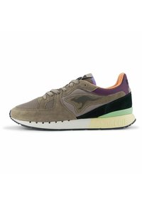Sneaker con una combinazione di suede marrone e tomaia in mesh, accenti neri e verdi, pannello posteriore viola e suola bianca con il testo "DYNACOIL".