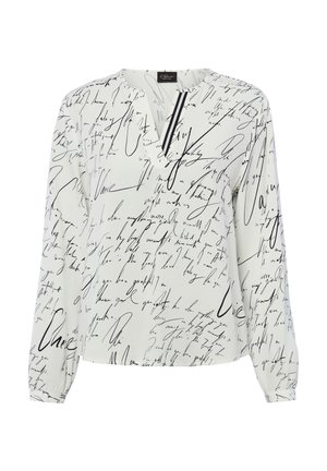 Witte blouse met lange mouwen, bedrukt met zwarte handgeschreven letters en een kleine V-hals met twee verticale zwarte strepen bij de halslijn.