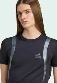 Zwart sportieve t-shirt met zilveren accenten en adidas-logo. Heeft een slim-fit ontwerp met korte mouwen en een ronde hals. Gladde textuur.