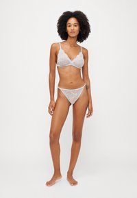 Satsi bralette dan thong dalam warna biru lembut dengan pola bunga yang rumit, dilengkapi dengan tali yang dapat disesuaikan dan hiasan yang anggun.