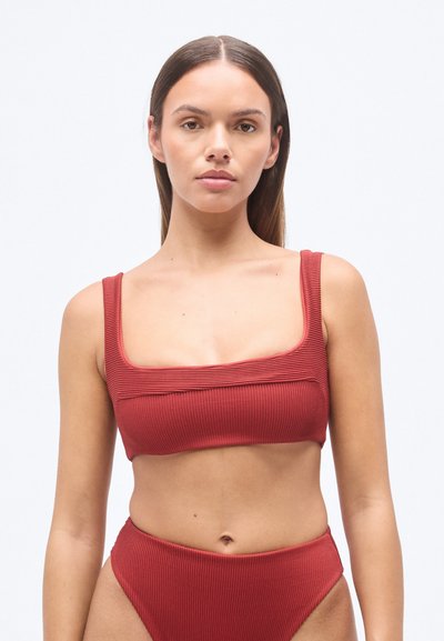 Ensemble bikini rouge côtes, composé d'un haut à encolure carrée avec larges bretelles et d'un bas taille haute, présentant une texture lisse et une coupe ajustée.
