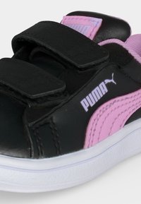 Μαύρο και ροζ αθλητικό παπούτσι Puma με δύο μαύρες λουρίδες με βέλκρο και λευκή σόλα, με το λογότυπο Puma στο πλάι και στη γλώσσα.