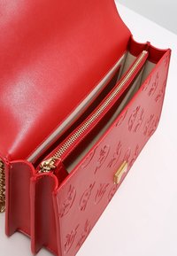 Borsa a mano rossa in pelle con motivi stampati, hardware dorato e tasca interna con zip. Texture liscia e design strutturato.