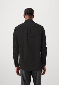 Black long-sleeve shirt with a tailored fit, buttoned cuffs, and a back pleat, made from a smooth fabric.