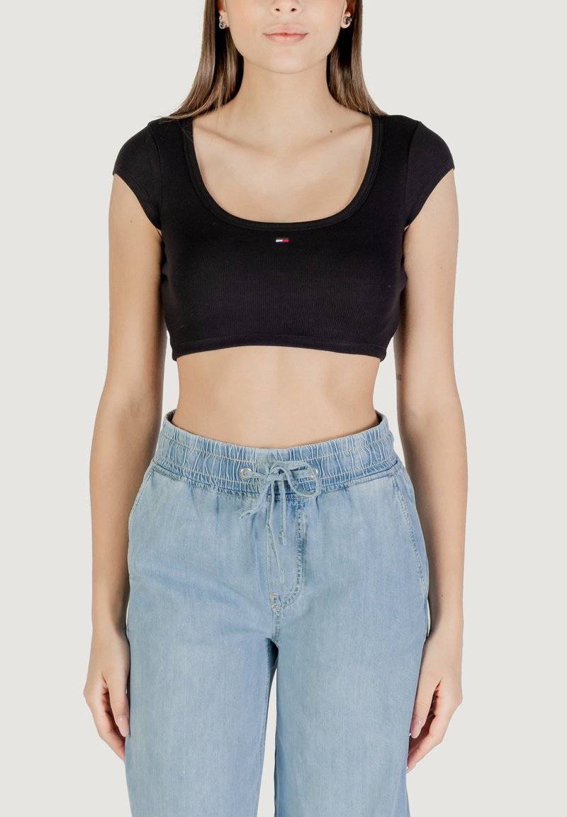Top nero corto in tessuto a coste con maniche corte e scollo a girocollo, abbinato a pantaloni azzurri con coulisse.