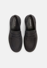 Sorte slip-on sko med glatt skinn øvre, rund tå, subtil sløyfe detalj på vampsiden, og sydd detaljer langs sålen.