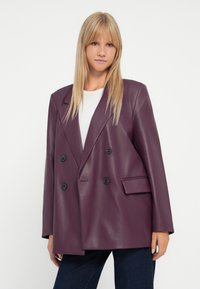 Dvojřadý blazer z tmavě fialkové umělé kůže, s černými knoflíky, strukturovanými rameny a jednou náprsní kapsou.