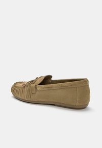 Mocassino in suede marrone chiaro con dettagli cuciti, fiocco sopra e suola piatta in gomma, visto da un'angolazione laterale bassa su sfondo bianco.