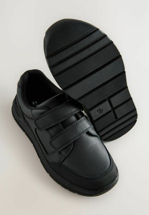 Sorte velcro sneakers med en glat læderoverdel og en struktureret gummisål med udtalte mønstre for greb. Minimalistisk design.