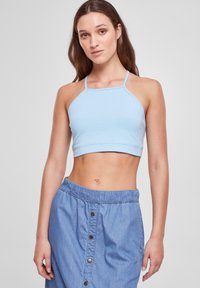 Svijetloplava halter crop majica s tankim trakama, napravljena od glatkog materijala. Uparena s traper suknjom s gumom u struku i gumbima.