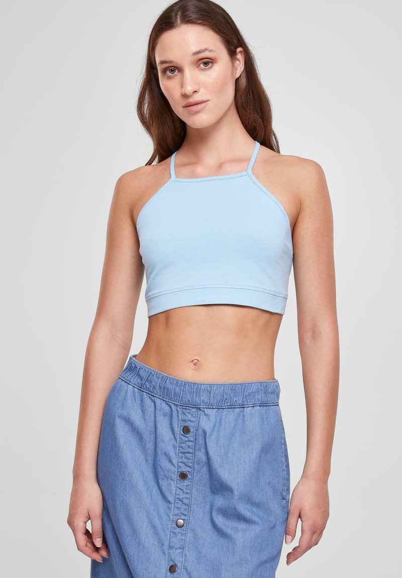 Svijetloplava halter crop majica s tankim trakama, napravljena od glatkog materijala. Uparena s traper suknjom s gumom u struku i gumbima.