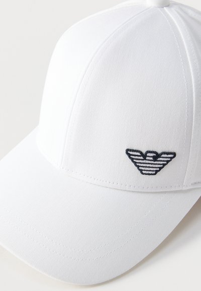 Valge kõverdatud äärega pesapalli nokats, millel on esipaneelil tikitud must-valge triibuline kotkalogo.