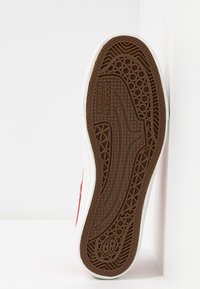 Semelle de chaussure de sport blanche avec motif de bande de roulement en caoutchouc marron et marquage "Dockers by Gerli Footwear" visible sur la semelle.