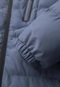 Niebieska kurtka puchowa z pikowanym wzorem. Rękaw ma marszczony mankiet i gładką fakturę, z kontrastującym suwakiem.