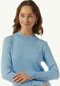 Lichtblauwe pullover sweater van zachte gebreide stof, met een geribbelde halslijn en knoopaccenten op de mouwen. Getailleerd ontwerp met lange mouwen.