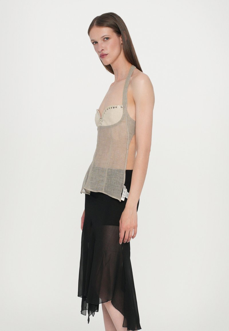 Beige and gray crop top with a structured bust, thin straps, and decorative studs, paired with a flowing black shear skirt.