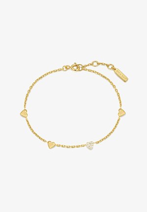 Bracelet chaîne en or avec quatre breloques en forme de cœur, un cœur orné de petites pierres claires, et un fermoir avec une étiquette de marque gravée.