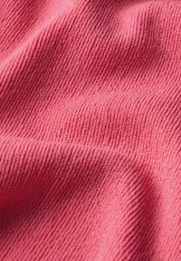 Strukturierter Stoff in lebhaftem Pink mit schmalen Rippungen. Die Oberfläche erscheint weich und leicht dehnbar und fängt das Licht subtil ein.