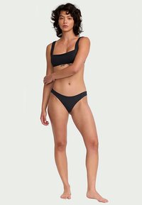 Čierny bikinový set s topom so štvorcovým výstrihom a širokými ramienkami, doplnený nízkymi tangami. Hladká tkanina s minimalistickým dizajnom.