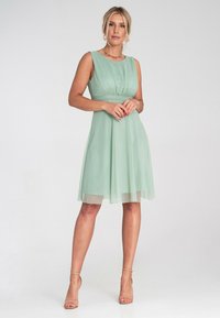 Miętowa sukienka bez rękawów z dopasowanym gorsetem i zwiewnym spódnicą z szyfonu. Posiada zgromadzony pas i lekko warstwowy dół.