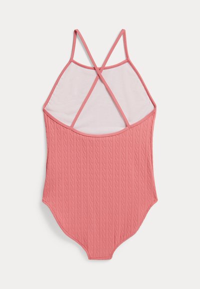 Rožinė vientisa maudymosi apranga su tekstūruotu vertikaliu pynimo raštu ir susikertančiomis petnešėlėmis ant balto fono.