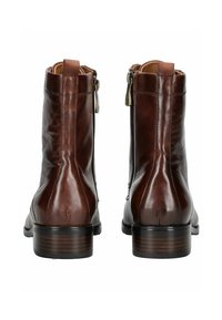 Botas de cuero marrón hasta el tobillo con una textura suave, cierre de cremallera en el lado y un tacón de madera apilada. Presenta un sutil detalle de costuras.