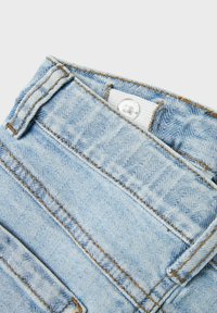 Jeans en denim bleu clair avec des coutures orange contrastantes, une taille courbée et une fermeture à bouton supérieur. Comprend des poches arrière standard.