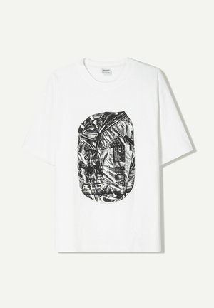 T-shirt en coton blanc avec un graphique noir et argent d'une canette froissée, à coupe ronde et ample, avec des manches courtes.