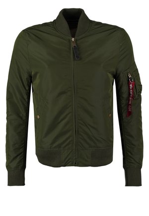 Chaqueta bomber verde oliva hecha de nylon, con frente de cremallera, puños acanalados, dos bolsillos laterales y un bolsillo en el brazo con cremallera y una etiqueta roja.