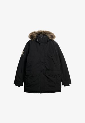 Giacca parka nera con cappuccio foderato in pelliccia sintetica, due tasche frontali, chiusura a bottoni a pressione e una toppa sulla manica sinistra. Tessuto liscio.