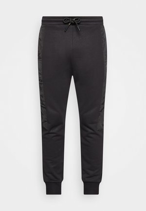 Black sweatpants with a drawstring waist, featuring smooth fabric and contrasting shiny panels along the sides. Cuffs at the ankles.